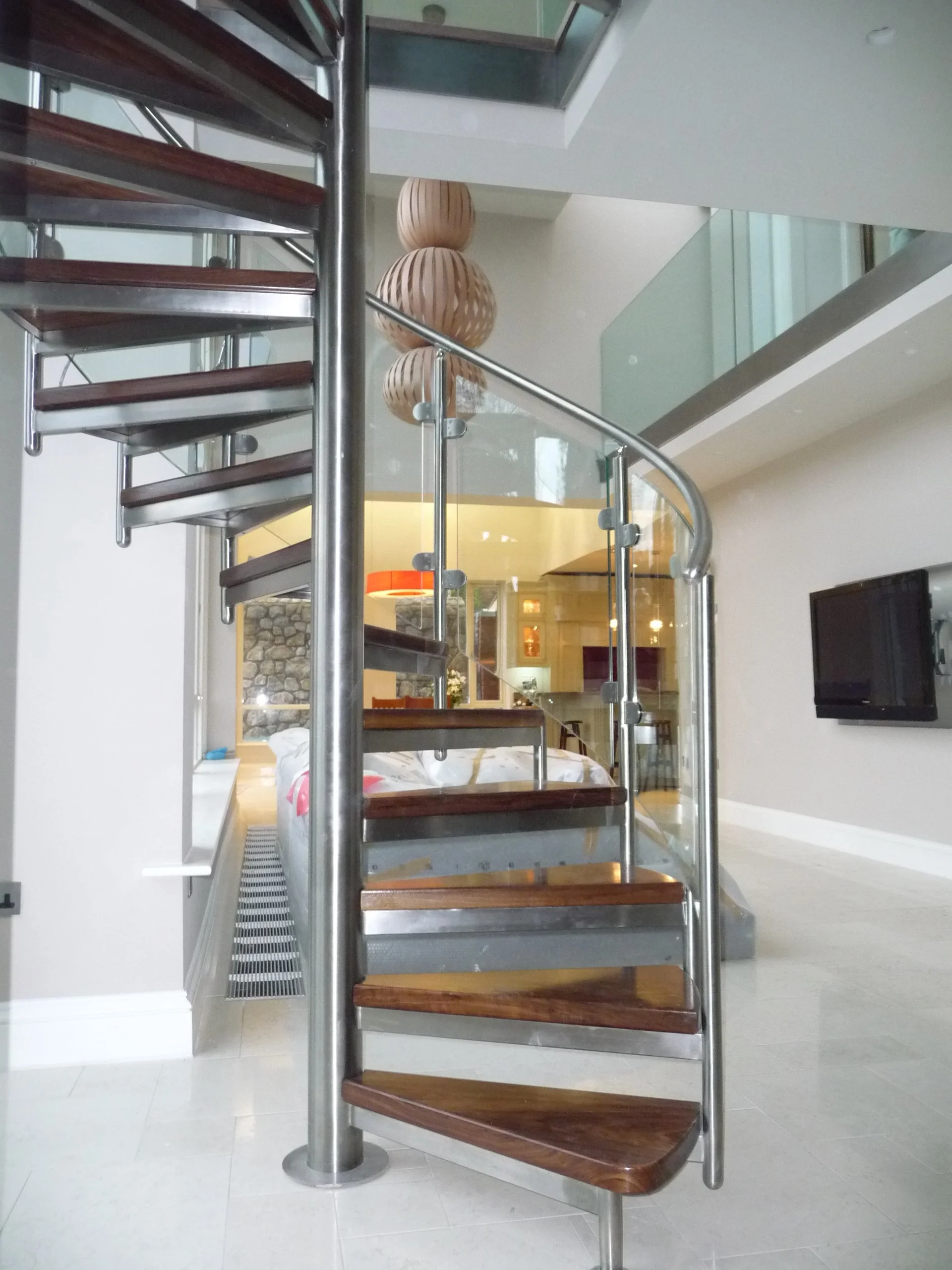 ‘Palmerston’ Walnut Spectral.
‘Spectral’ style Spiral Stairs fully Stainless Steel with Curved Glass Infill and 2″ thick Walnut Treads.