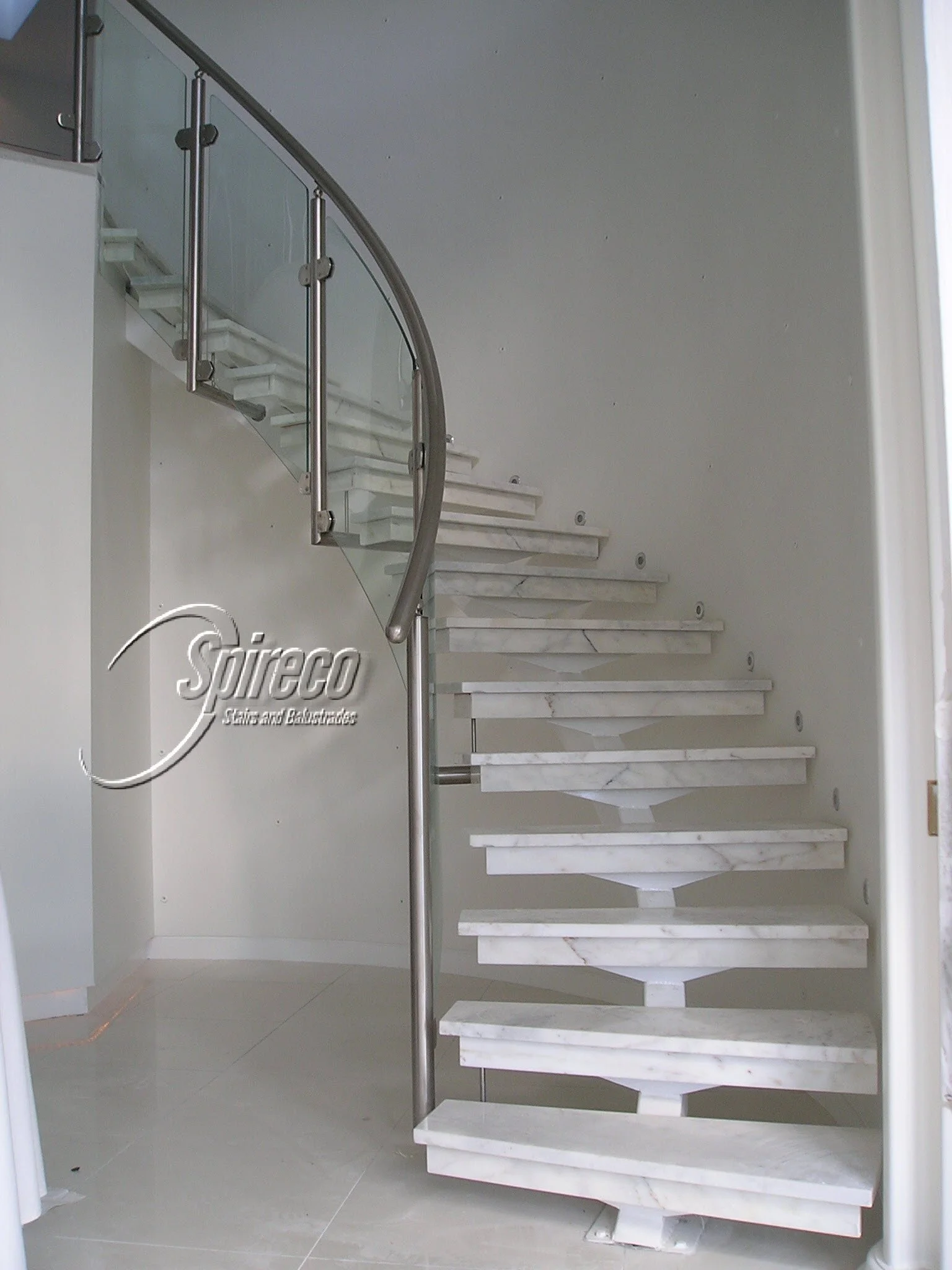 Curved Central Spine Stairs.
Curved Steel Central Spine with Marble treads and side mounted Stainless Steel with Curved Glass infill Balustrade.
