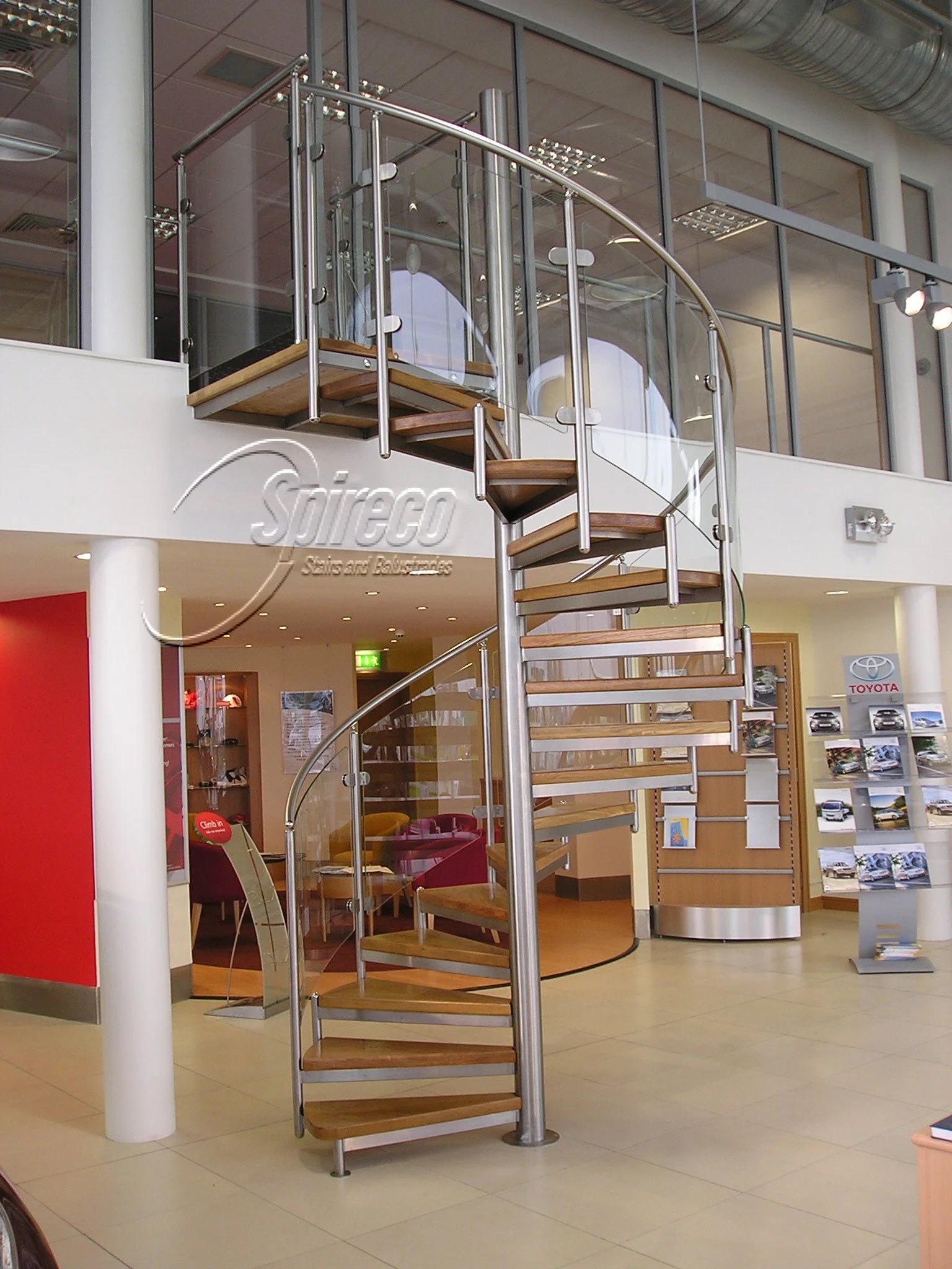 ‘Spectral’ Spiral Stair.
Polished fully Stainless Steel framed Spiral Stair with Curved Glass infill Balustrade and 2″ Oak treads.