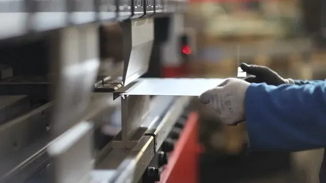 Worker wearing gloves operating industrial machine.