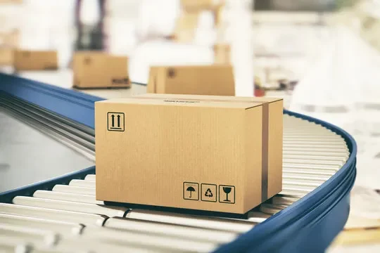 Cardboard box on a conveyor belt in a warehouse.