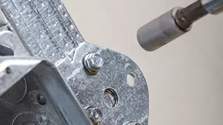 Close-up of a metallic mechanical component being worked on with a tool, possibly a soldering iron or a heat gun.