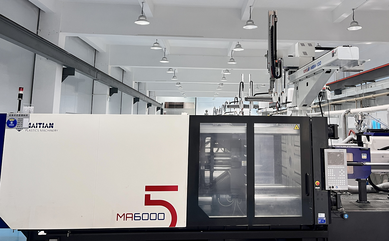 Industrial manufacturing or plastic molding machine in a factory setting with control panel and machinery components.