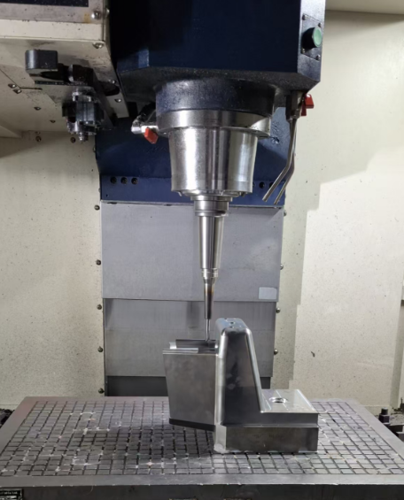 A CNC machine tool with a drill bit, machining a metal workpiece clamped on a worktable.