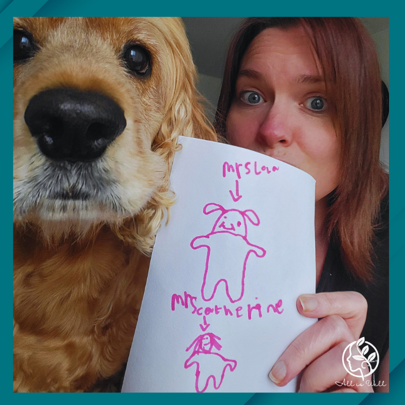 Catherine and Therapy Dog Lola holding a drawing of them by a child in pink pen.