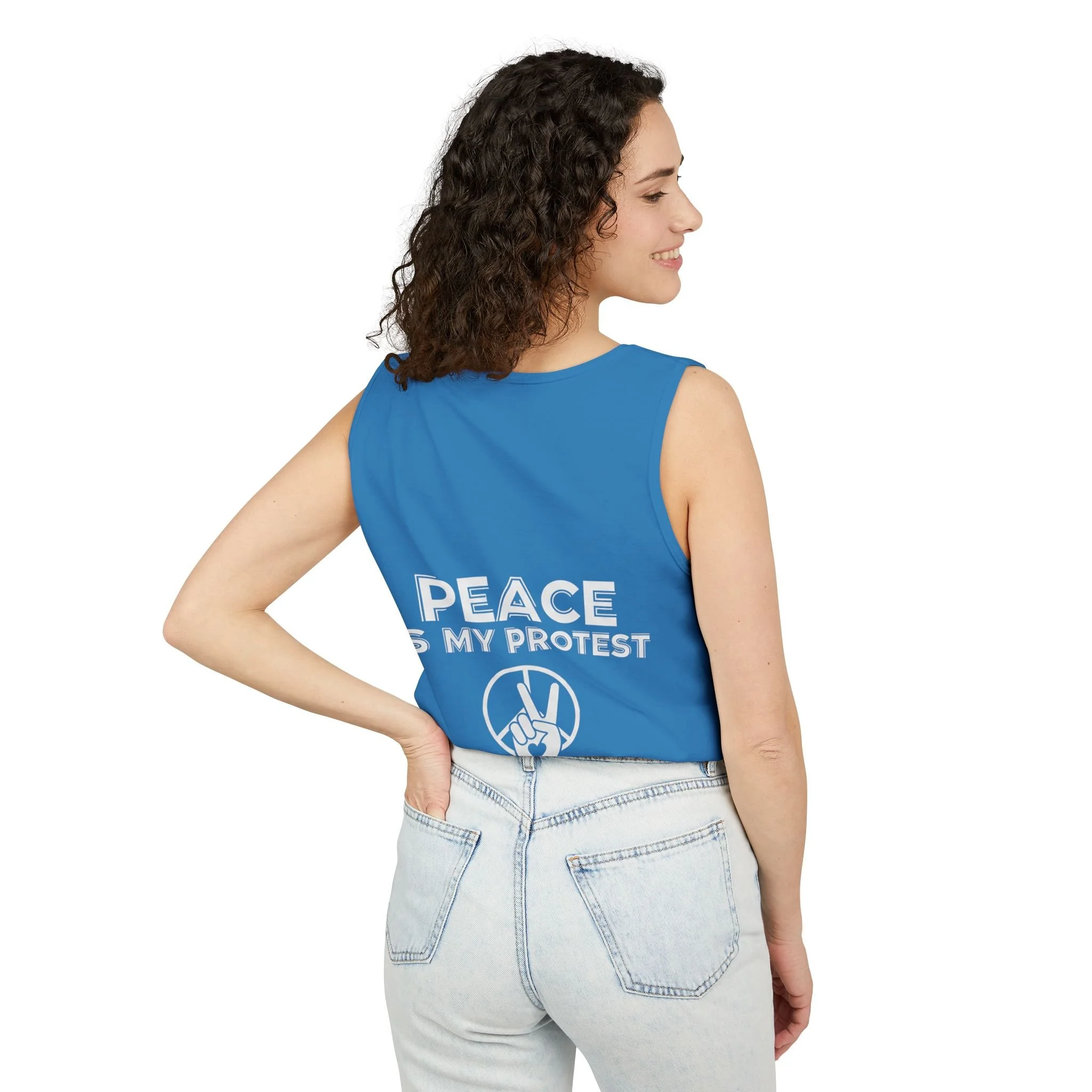 Woman with curly hair wearing a blue sleeveless shirt that reads 'PEACE IS MY PROTEST' and a peace sign, smiling and posing with her hand on her hip.
