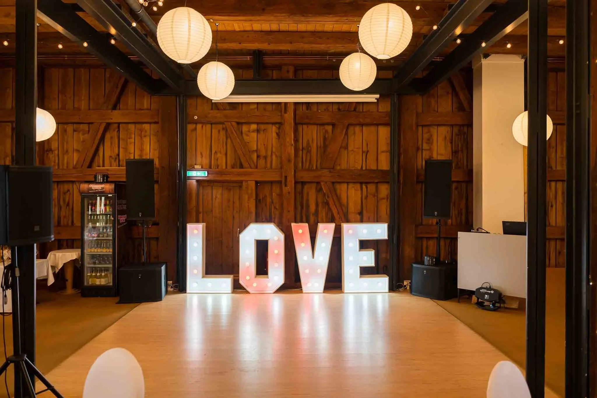 Leuchtende Buchstaben, die das Wort Love ergeben in einer festlich dekorierten Scheune