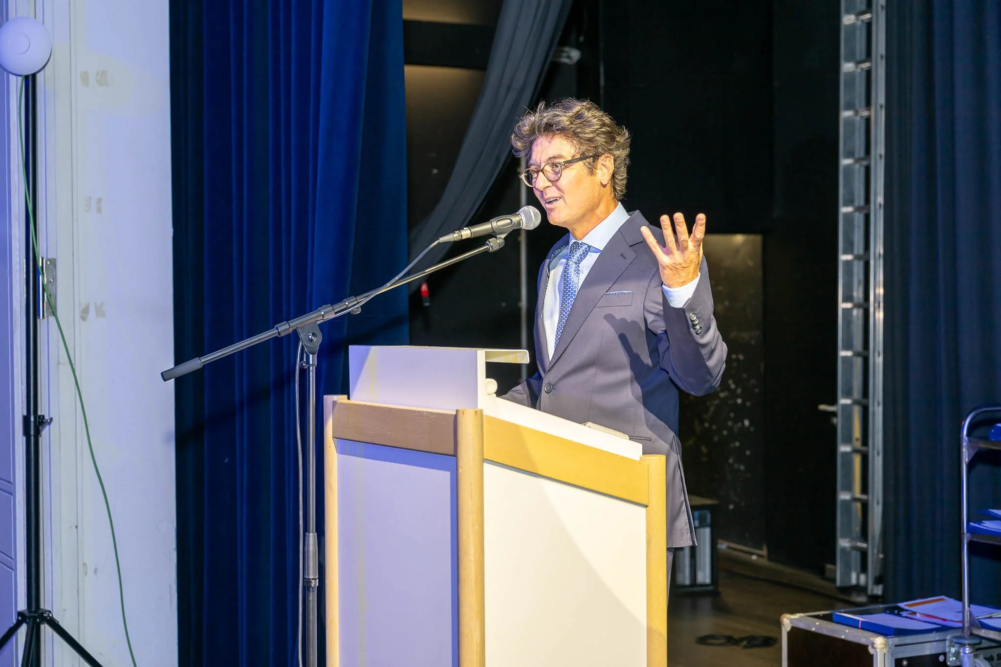 Ein Mann im Anzug und mit Krawatte hält eine Rede vor einem Publikum