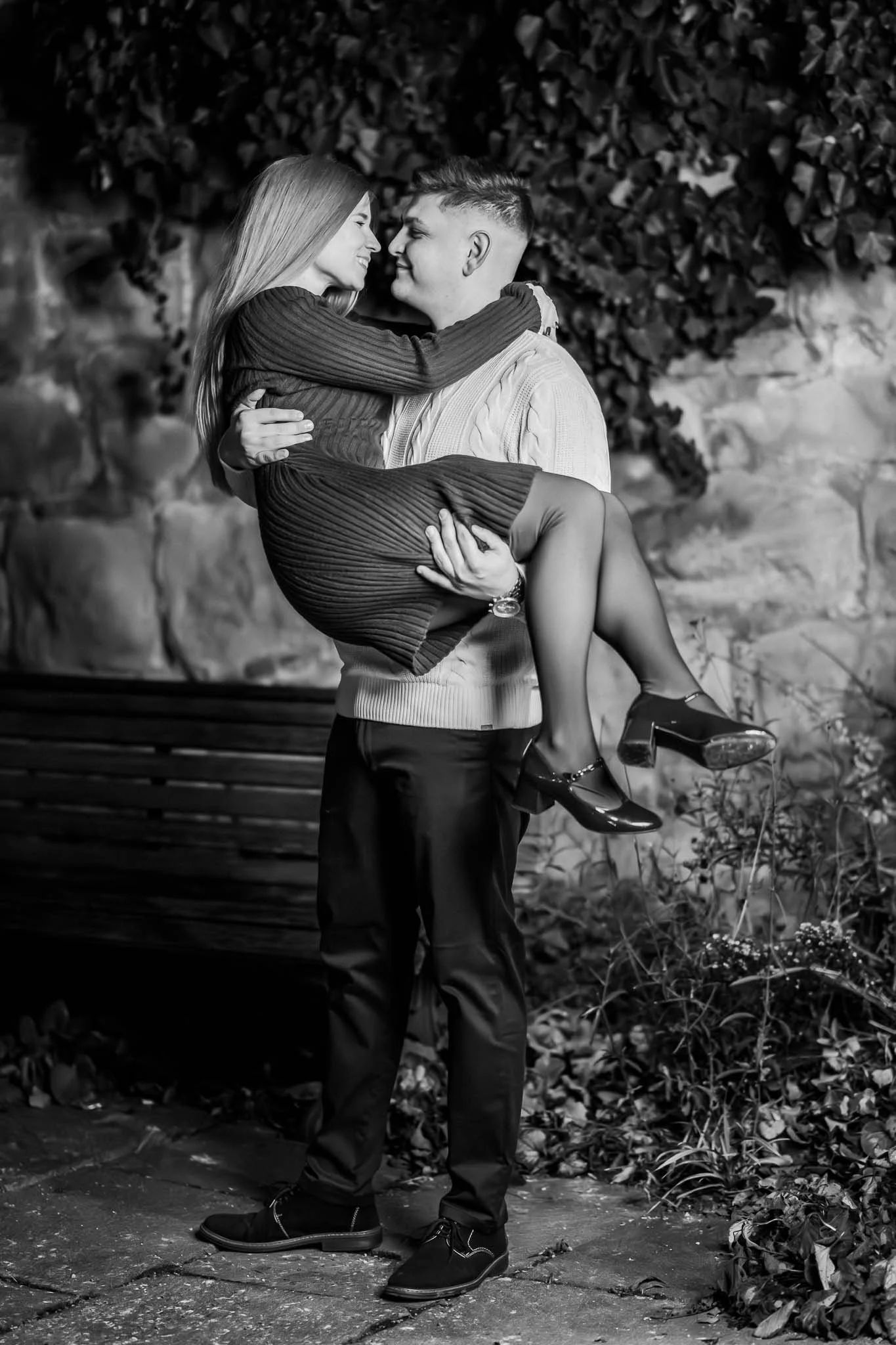 Schwarz-weiß Bild von einem Mann, der eine Frau in den Händen hält. Sie hat ihre Hände um seinen Hals gelegt und beide blicken sich liebevoll an.