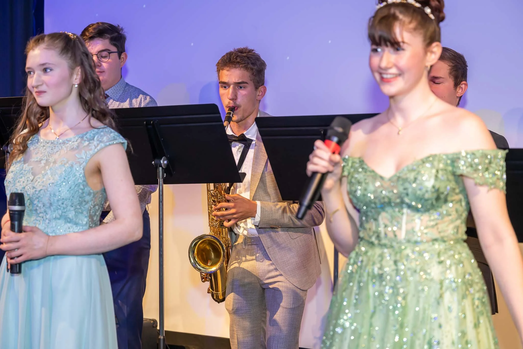 Eine Gruppe von Menschen in festlichen Kleidern singt fröhlich beim Abiball