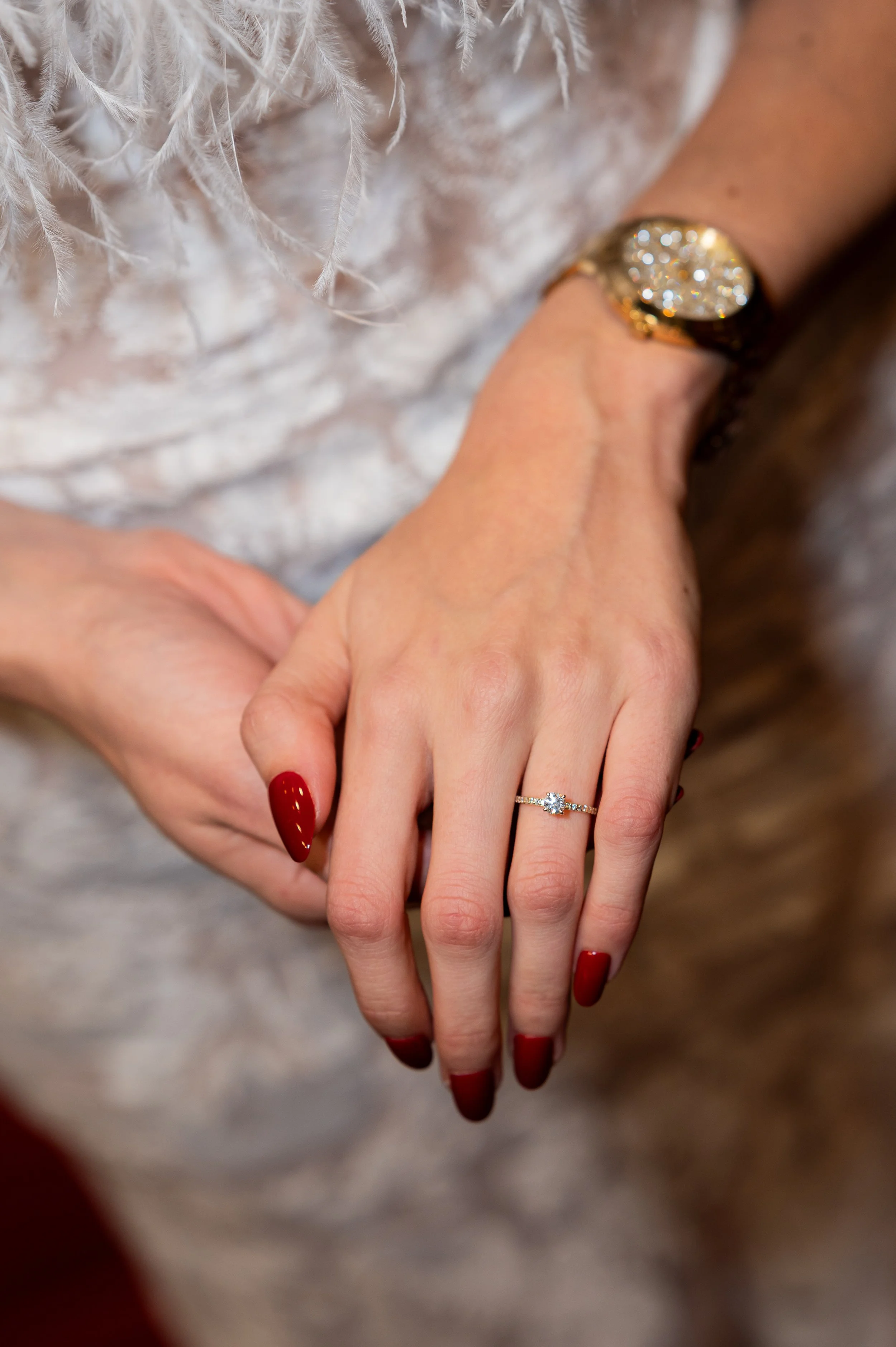 Nahaufnahme von einem Verlobungsring an einer zierlichen Hand mit roten Fingernägeln. Das Bild wirkt sehr dramatisch