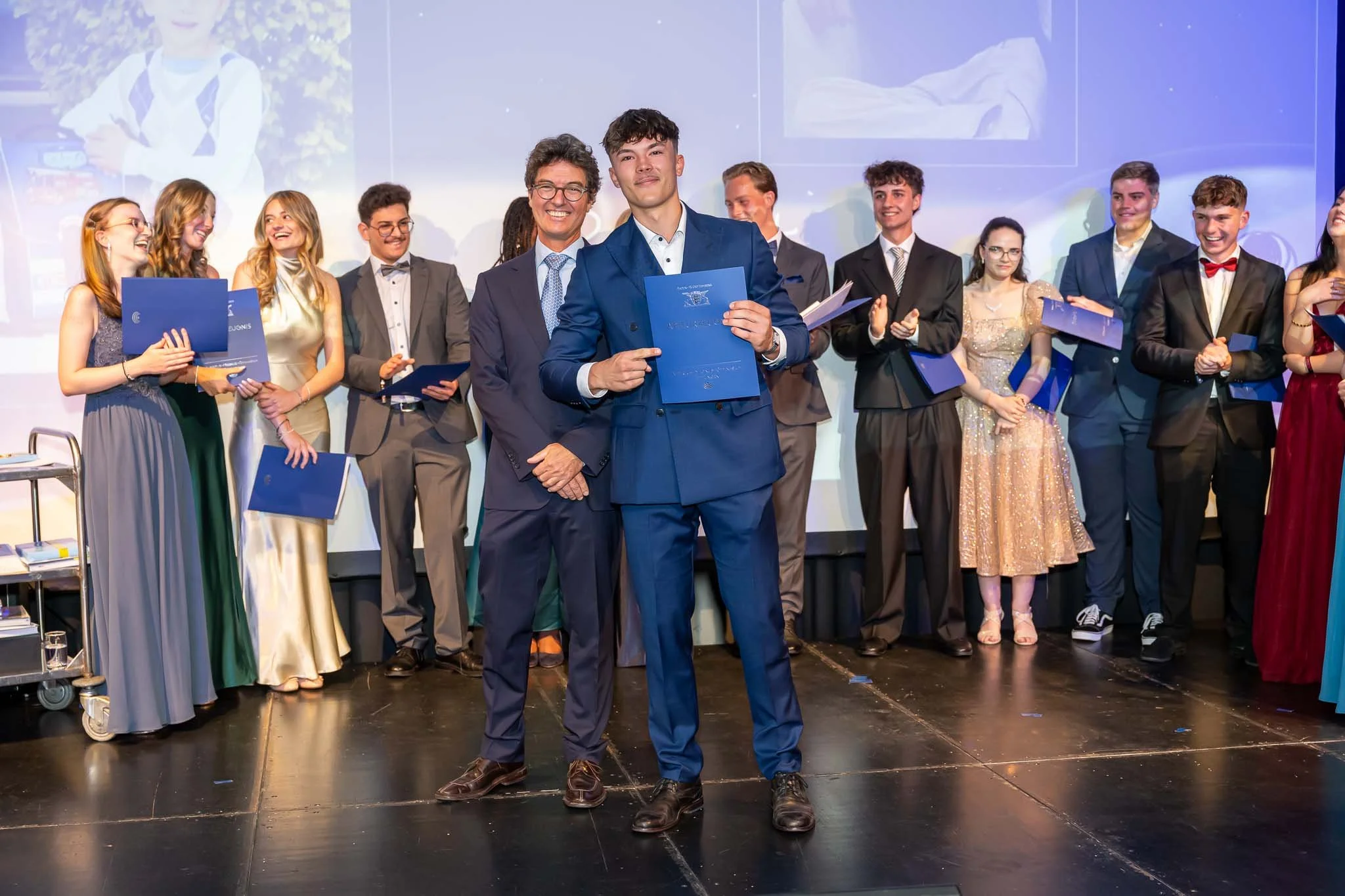 Schüler stehen auf der Bühne und präsentieren ihre Zertifikate während des Abiballs