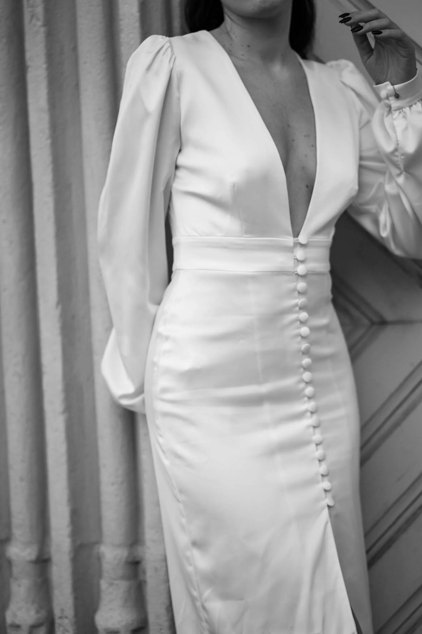 Nahaufnahme von einem weißen Kleid mit tiefem Ausschnitt und einer Knopfleiste vom Ausschnitt bis zum Saum