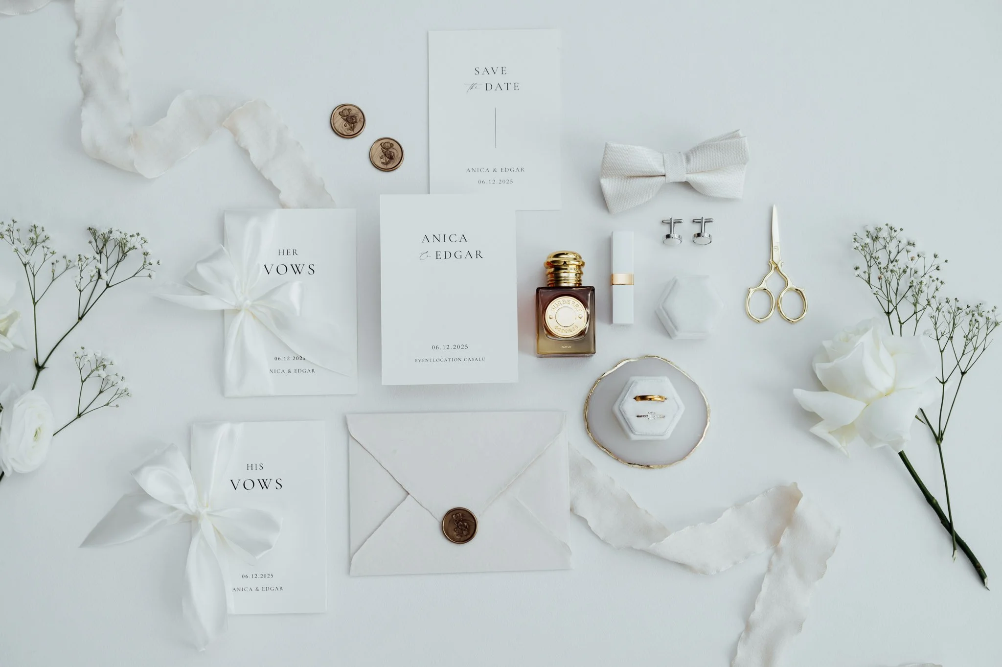 Weiße Einladungskarten, Brautaccessoires, Blumen, Schmuck und Deko-Elemente für eine Hochzeit auf einem weißen Tisch.