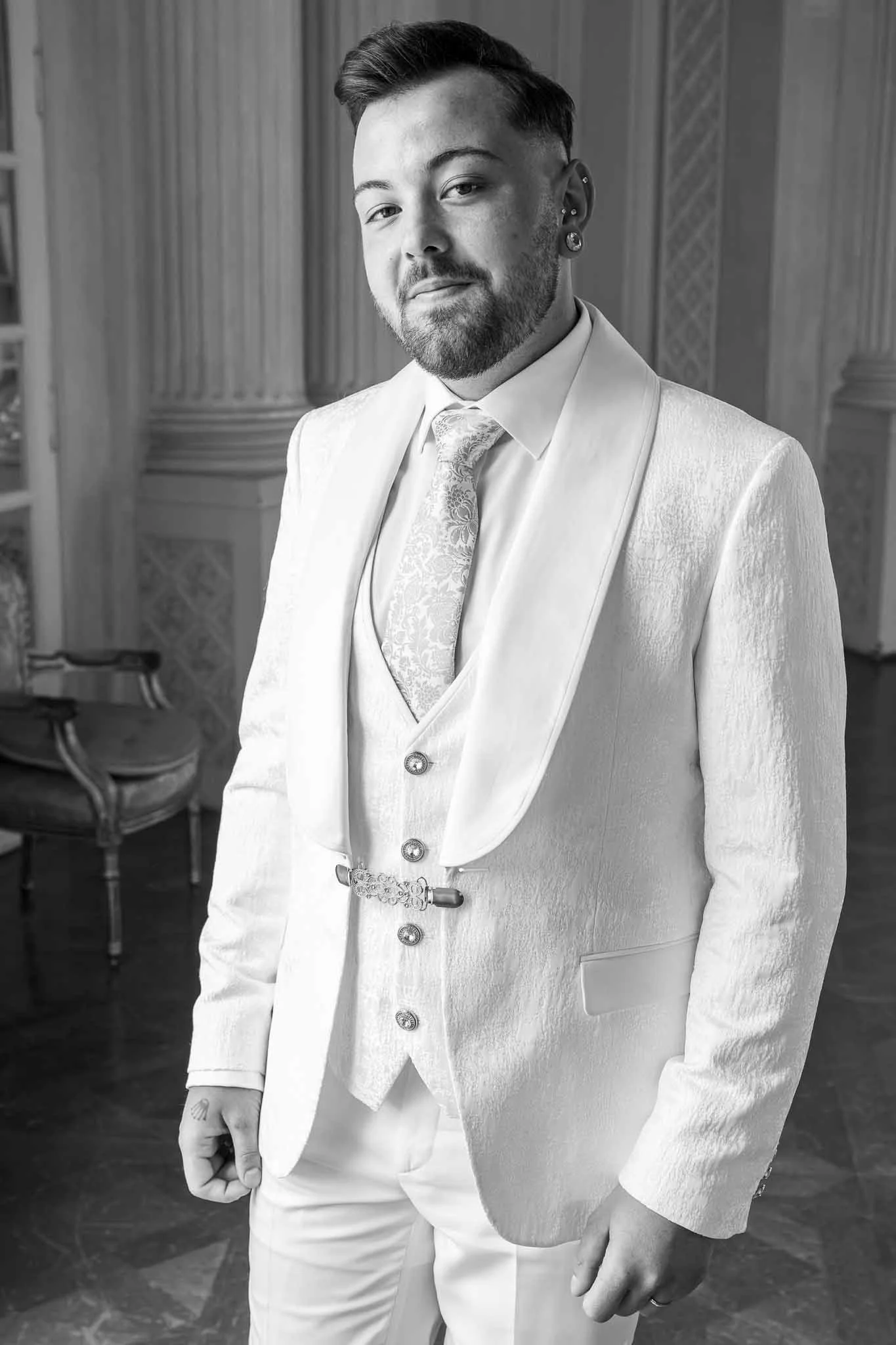Mann in formeller Kleidung, vermutlich Hochzeitsanzug, in einem eleganten Raum mit klassischen Möbeln.