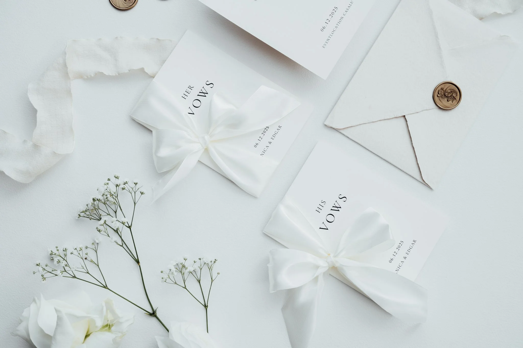 Weiße Hochzeitskarten, Umschläge mit Briefknoten, kleine weiße Blumen und Dekorationspapier auf einem weißen Hintergrund.