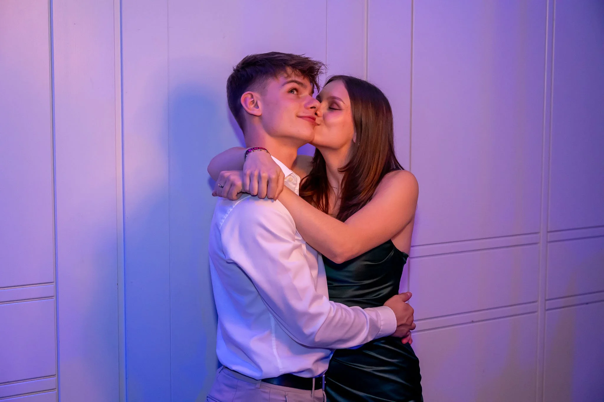 Ein junges Paar küsst sich vor einer blauen Wand, festgehalten beim Abiball vor der Fotokiste