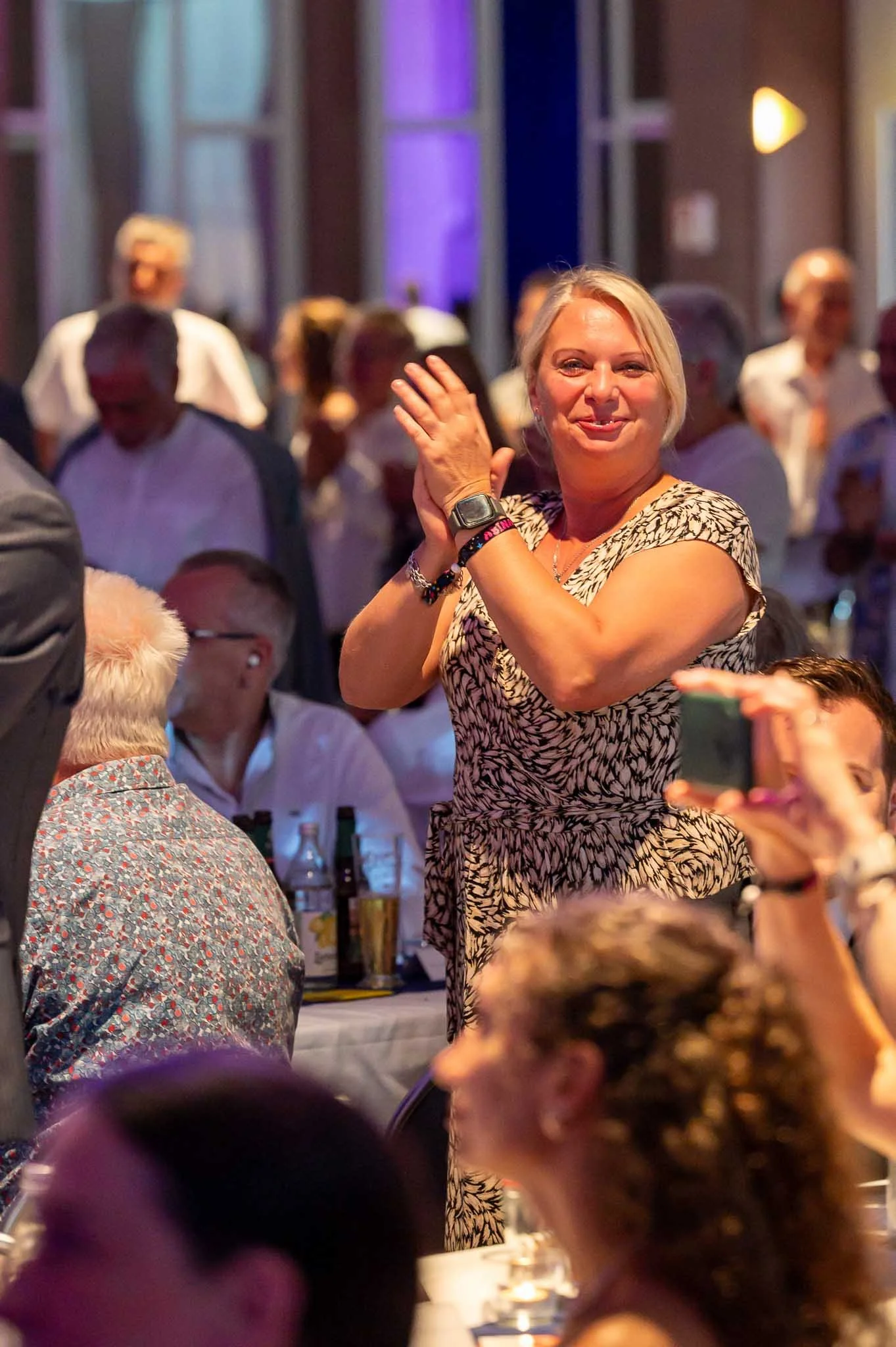 Eine Frau applaudiert fröhlich bei einem festlichen Abendessen