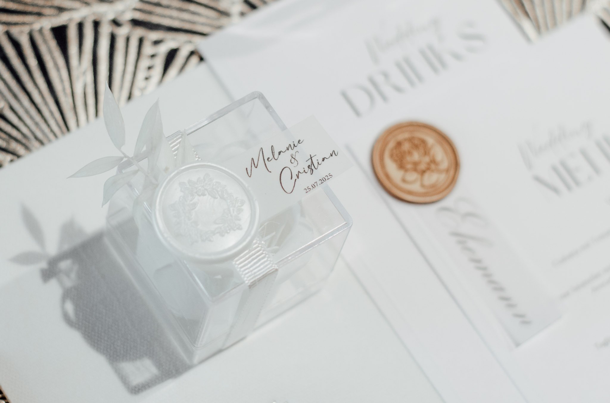 Weiße Hochzeitskarte mit goldener Briefmarke und einem kleinen, weißen Schachtel mit Namen Melanie und Christian sowie dem Datum 25.07.2025.