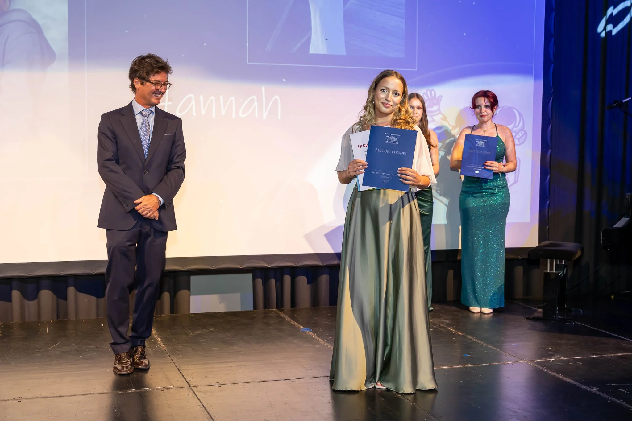 Eine Frau in einem langen Kleid hält stolz einen Preis beim Abiball