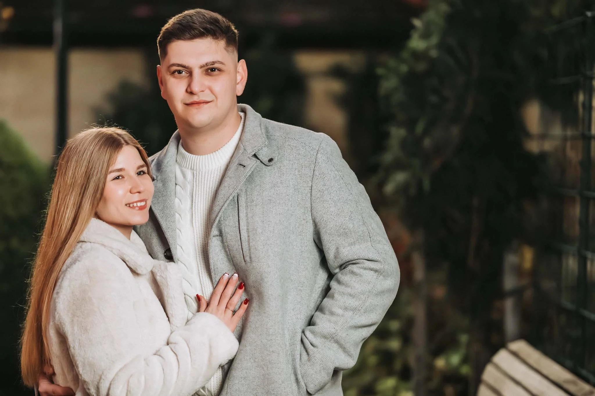 Halbkörper Porträt von einem Paar. Der Mann sieht direkt in die Kamera, während die Frau in die Ferne blickt. Beide tragen Mäntel