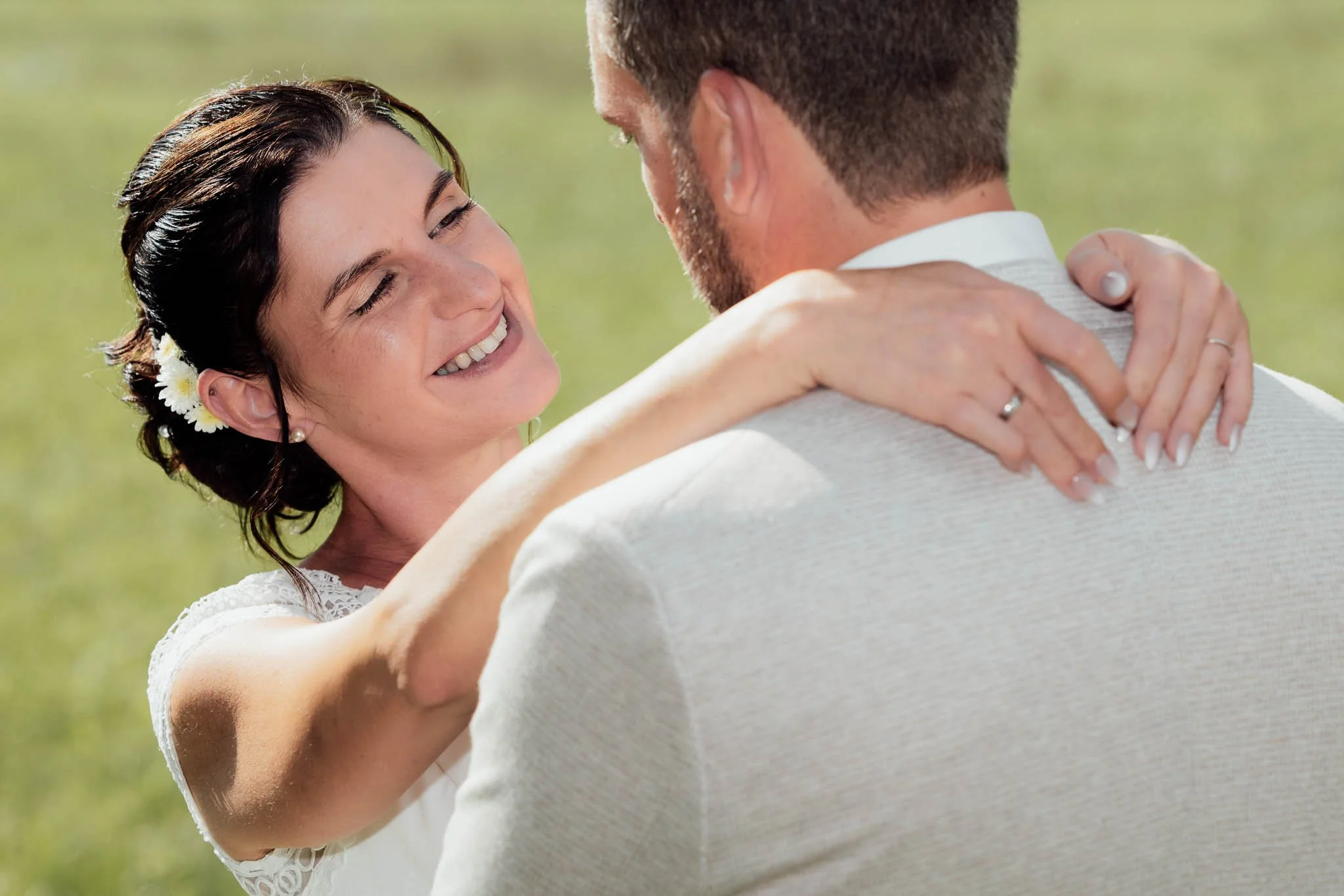 Ein lächelndes Brautpaar bei einer Umarmung im Freien.