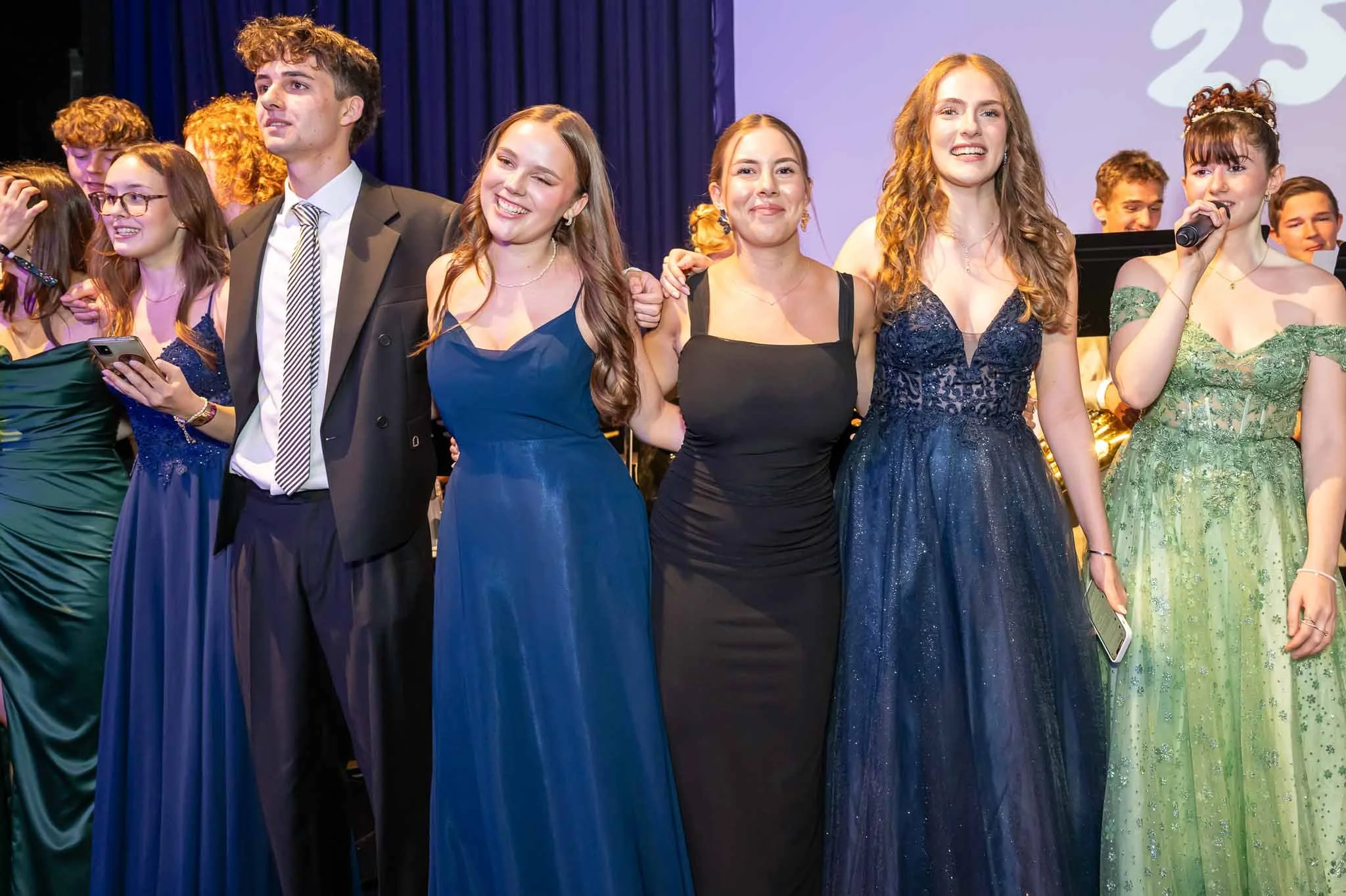 Eine Gruppe von Menschen in eleganten Kleidern und Anzügen steht zusammen, bereit für das Abiball-Event