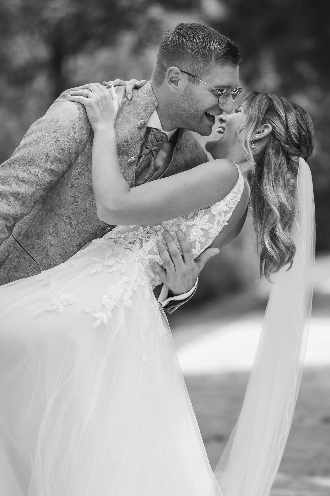 Schwarzweiß Bild von einem lachenden Brautpaar beim tanzen