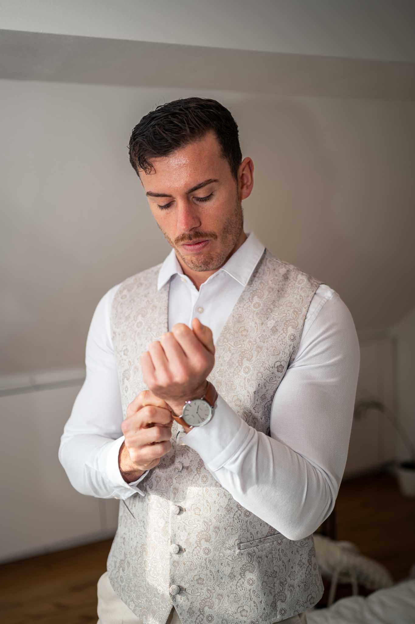 Mann im Anzug schließt gerade seine Uhr