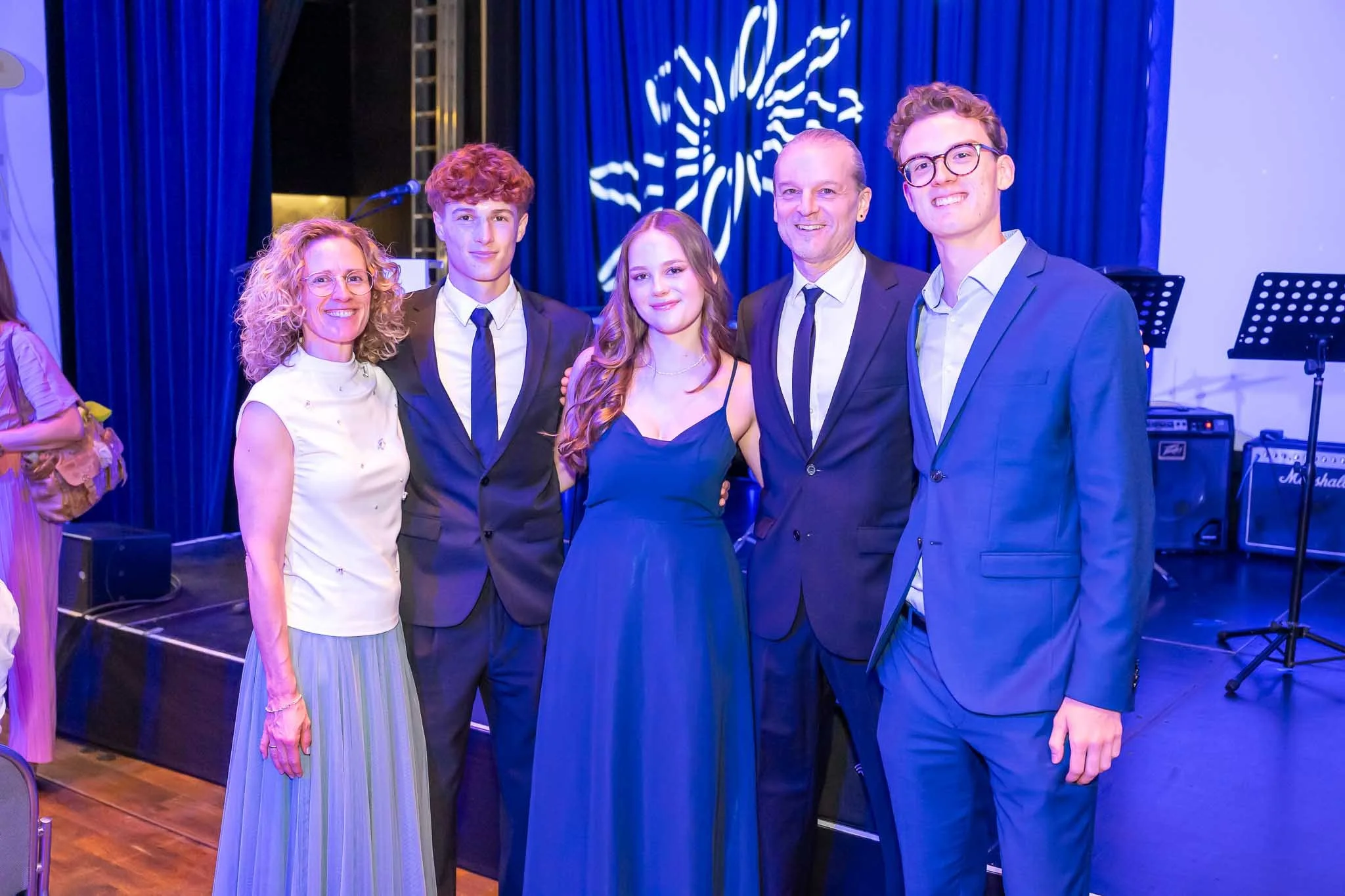 Eine Gruppe von Menschen in formeller Kleidung posiert fröhlich für ein Foto beim Abiball