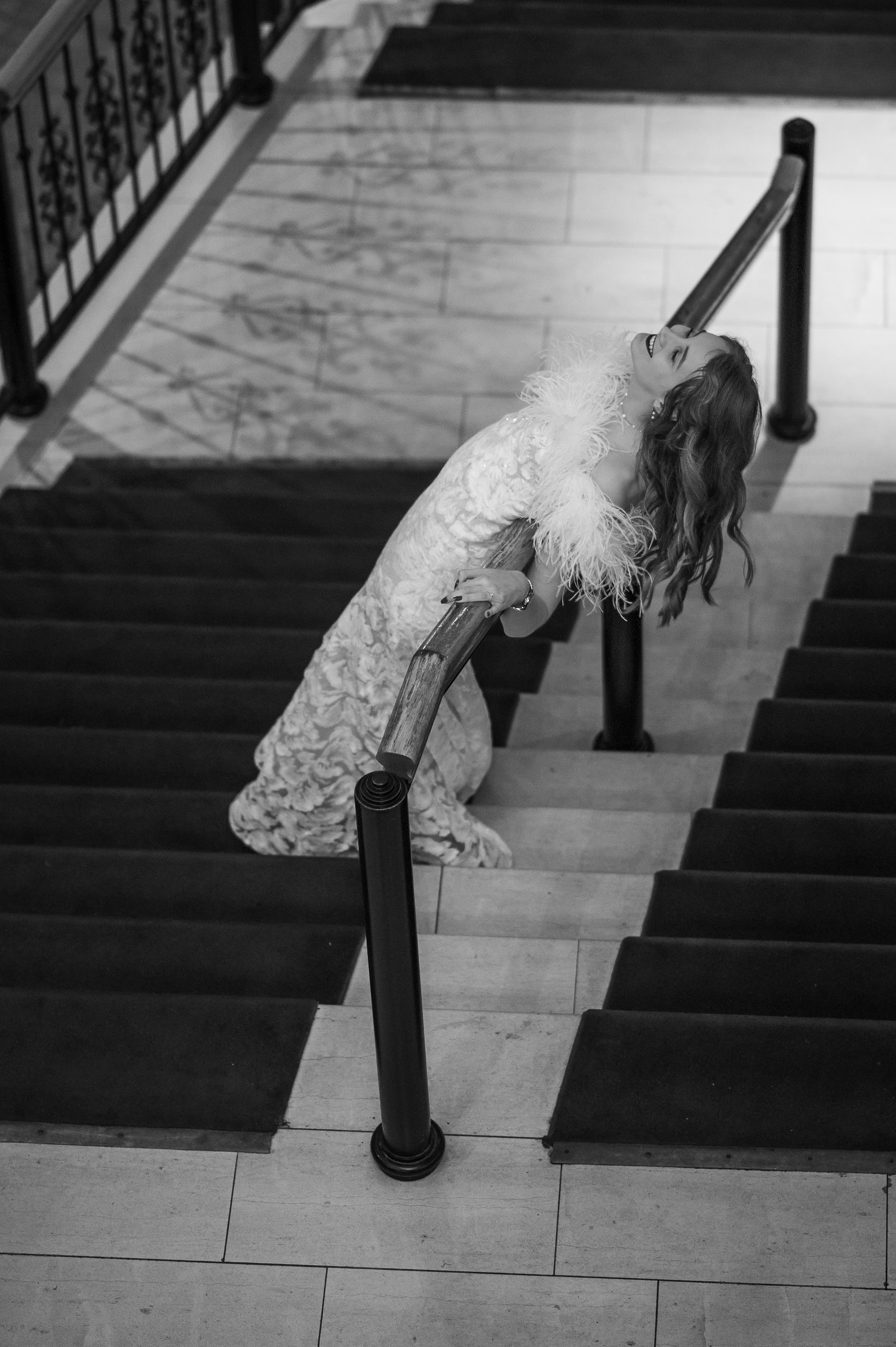 Ein schwarz-weiß Bild einer Braut, die sich rückwärts über das Geländer an einer Treppe hängen lässt