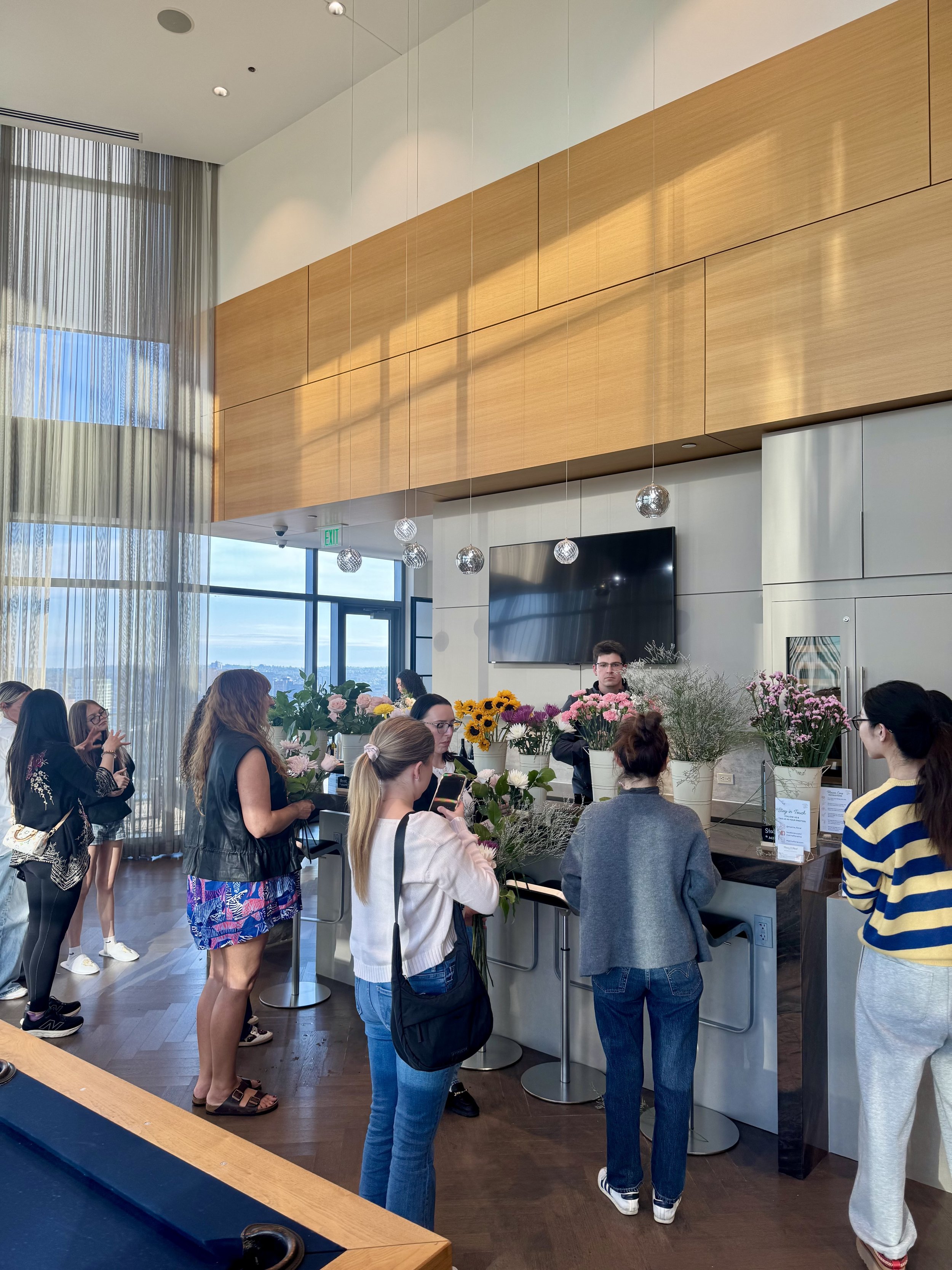 Guests picking out flowers and greenery to put together and build their own flower bouquets at a residential event in a luxury building in Boston.