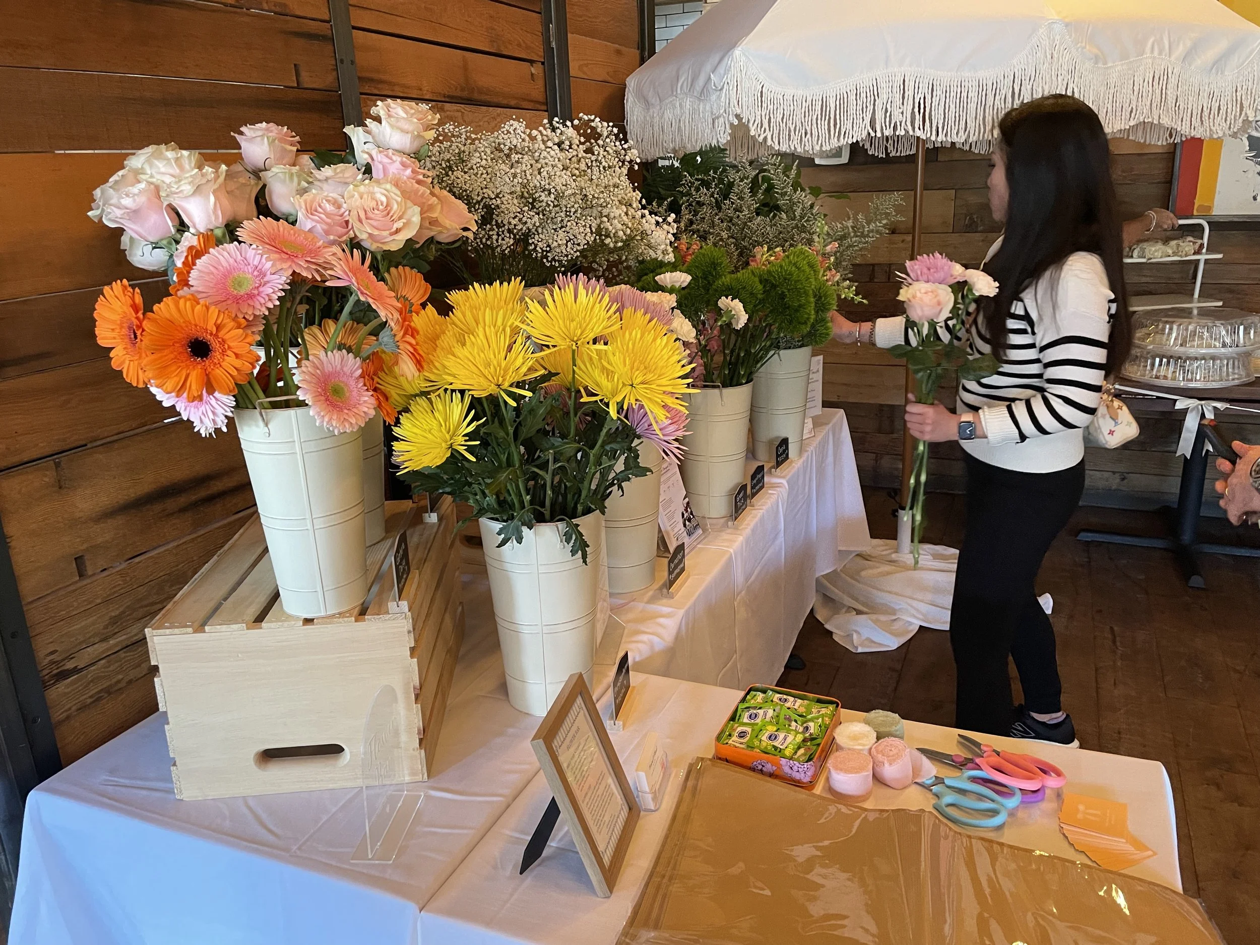A guest standing in front of a bloom bar at a bridal shower  is picking out flowers to build her own floral bouquet to take home as a party favor.