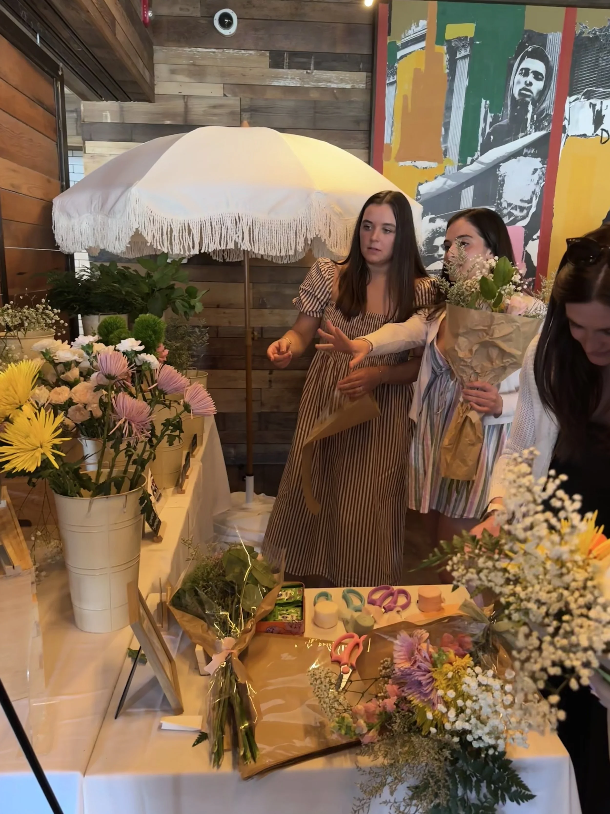 Guests standing at the bouquet bar setup are picking out their flowers and building their own floral bouquets at a bridal shower/baby shower.