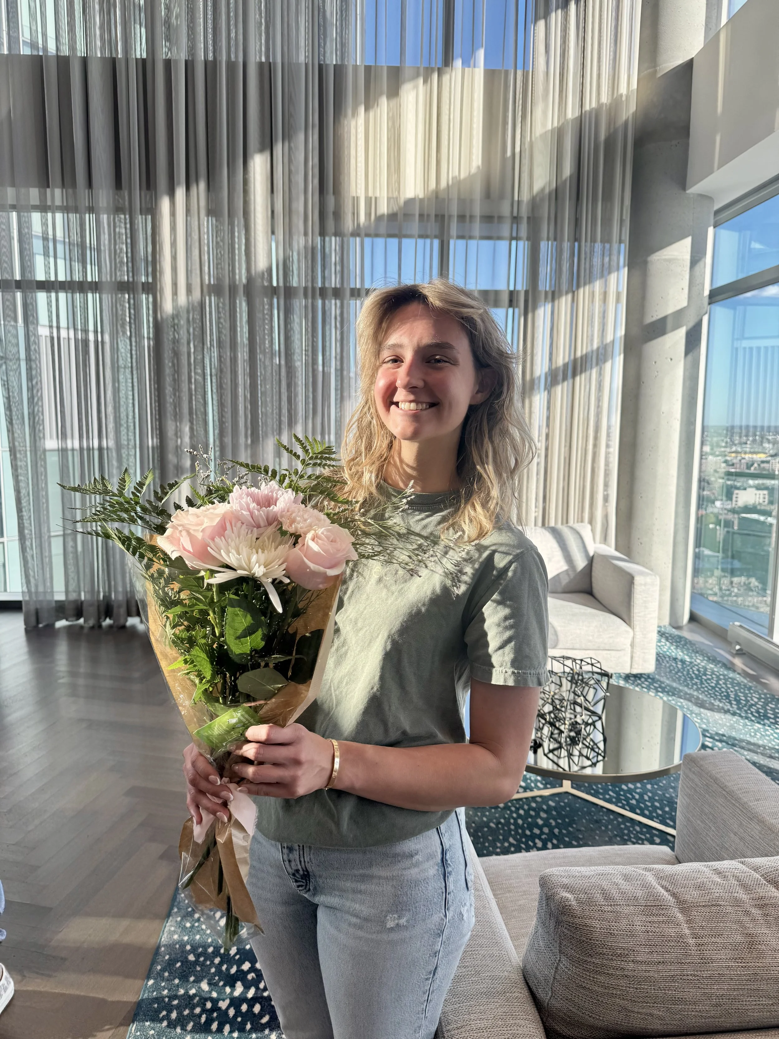 A smiling girl is holding a floral bouquet that she put together herself from the flower bar event in her residential building. 