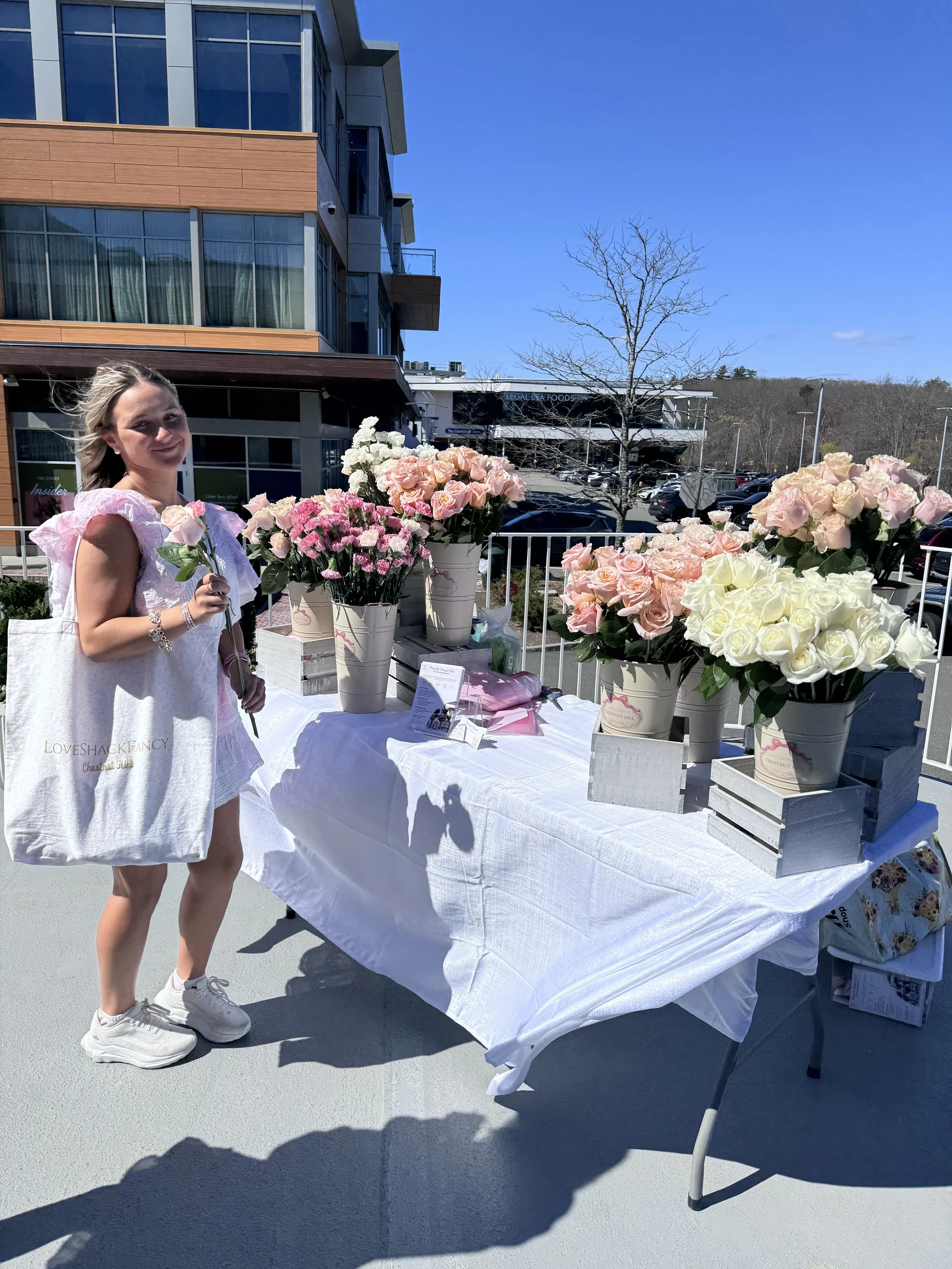 A girl at a LoveShackFancy brand activation event with a flower bar is picking out flowers to build her own bouquet to take home.
