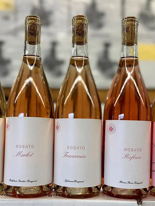 Three bottles of rosé wine with white labels that have red text, labeled 'Rosato Merlot', 'Rosato Francania', and 'Rosato Refoso'.