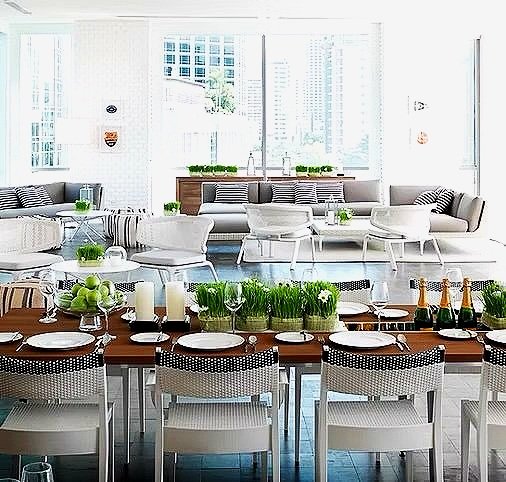Bright, modern living and dining area with white and gray furniture, large windows, and decorative greenery.
