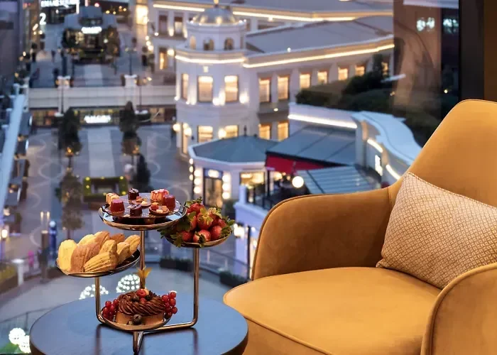 Tall modern skyscraper with a water feature and surrounding buildings at sunset.