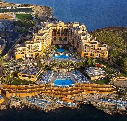 A large seaside resort with multiple pools, sunbathing areas, and a hotel complex overlooking the ocean.