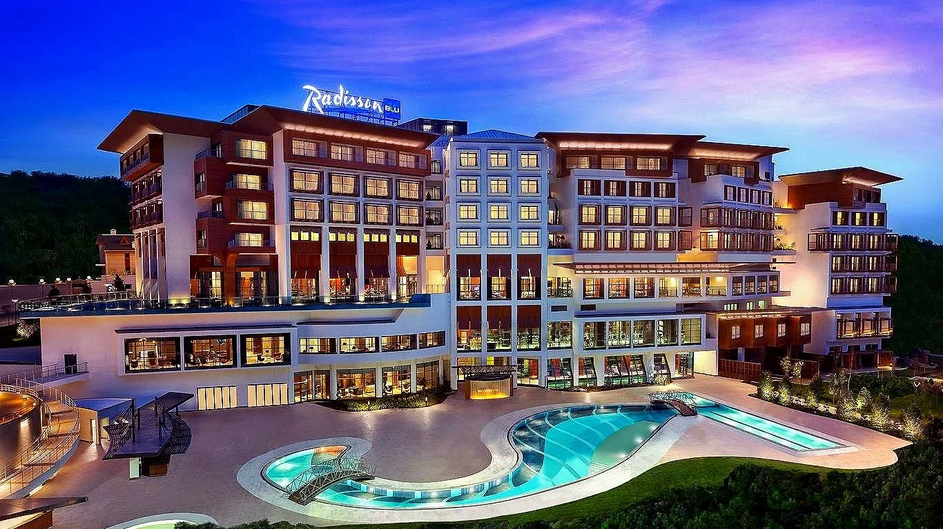 Night view of the Radisson Hotel & Spa with a large illuminated outdoor pool in the foreground and a clear sky above.