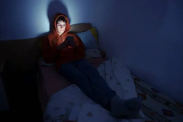 teenager-using-a-smartphone-lying-in-bed-late-at-night.webp