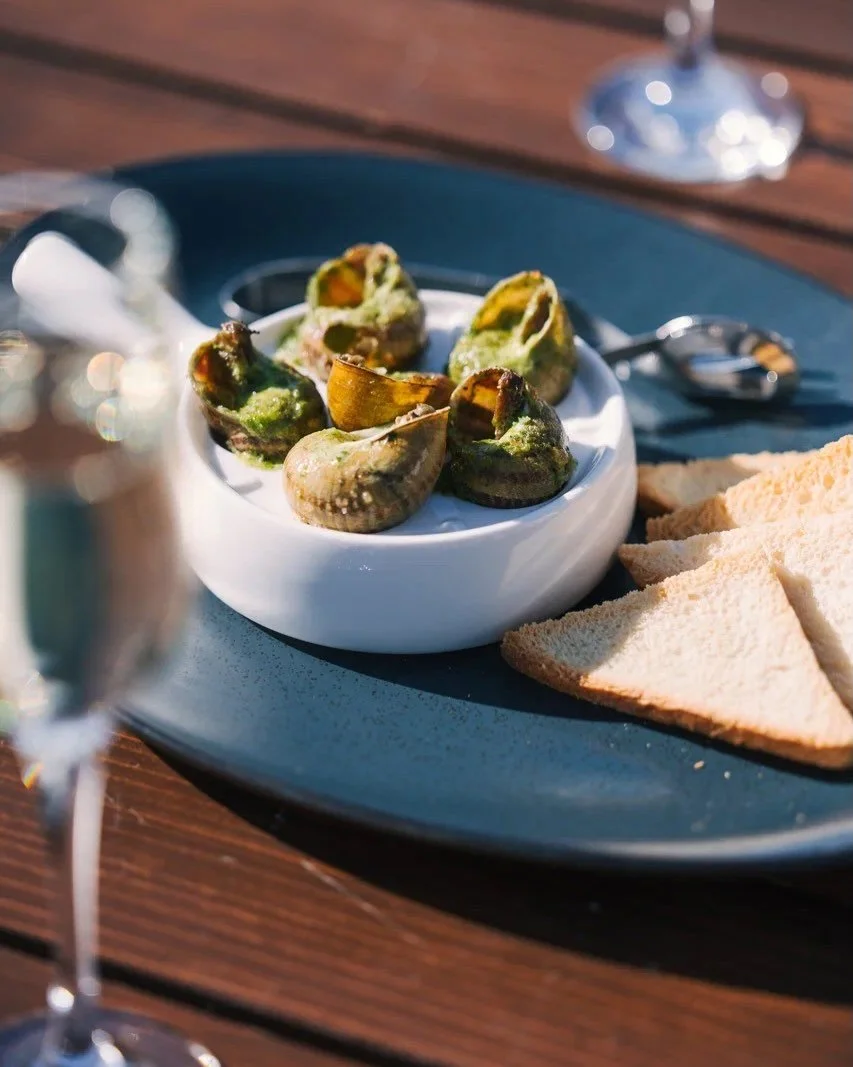 Roasted stuffed artichoke hearts served with sliced bread on a plate outdoors.