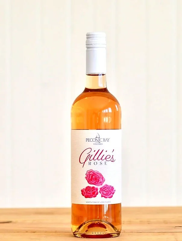 A bottle of Giddie's Rosé wine from Peconic Bay Vineyards on a wooden surface with a plain light background.