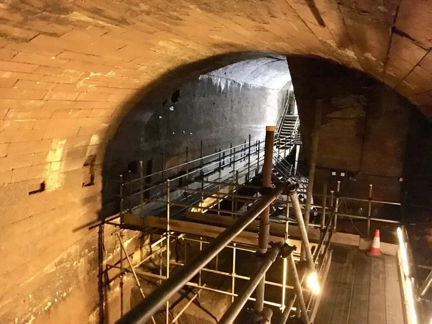 Underground tunnel with scaffolding and safety barriers for construction or maintenance.