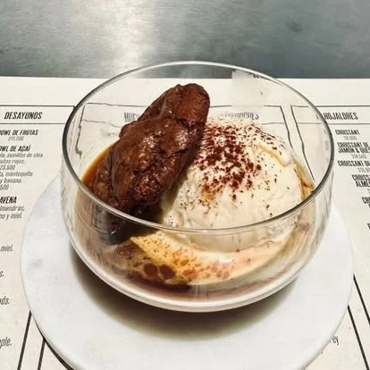 Dessert with vanilla ice cream, chocolate syrup, and a chocolate-covered wafer on top, served in a glass bowl.