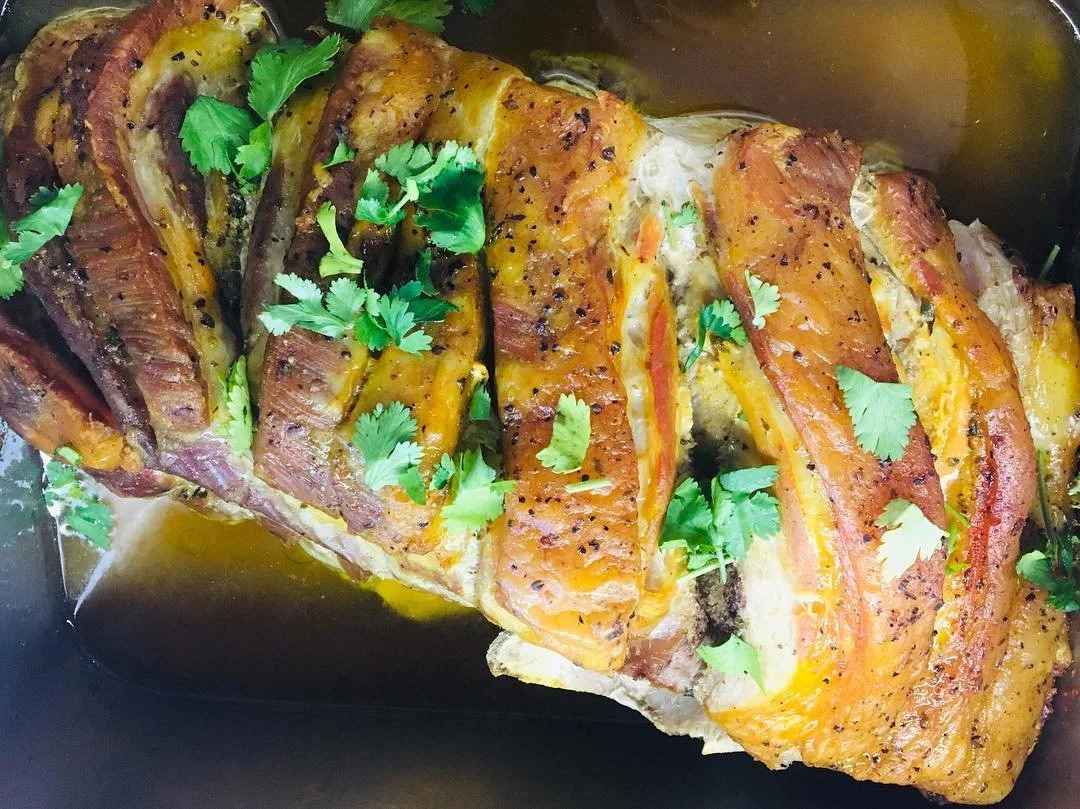 Baked or roasted piece of fish, garnished with fresh cilantro, with herbs and seasonings, topped with cooked vegetables, in a sauce or broth.