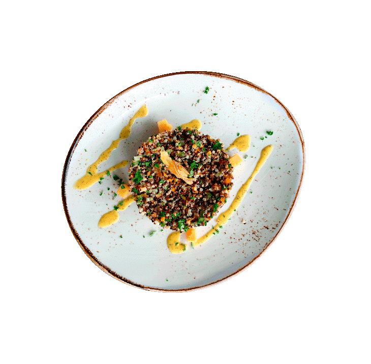 A plate of cooked quinoa garnished with herbs, with sauce drizzled on the plate, served on a white dish with a black background.