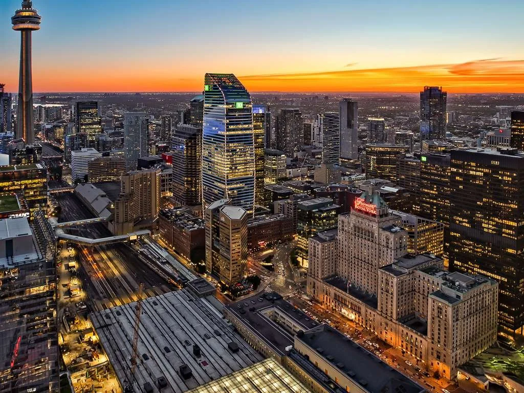 City skyline of downtown Los Angeles at sunset, featuring skyscrapers, the LA Union Station, and the illuminated city streets.