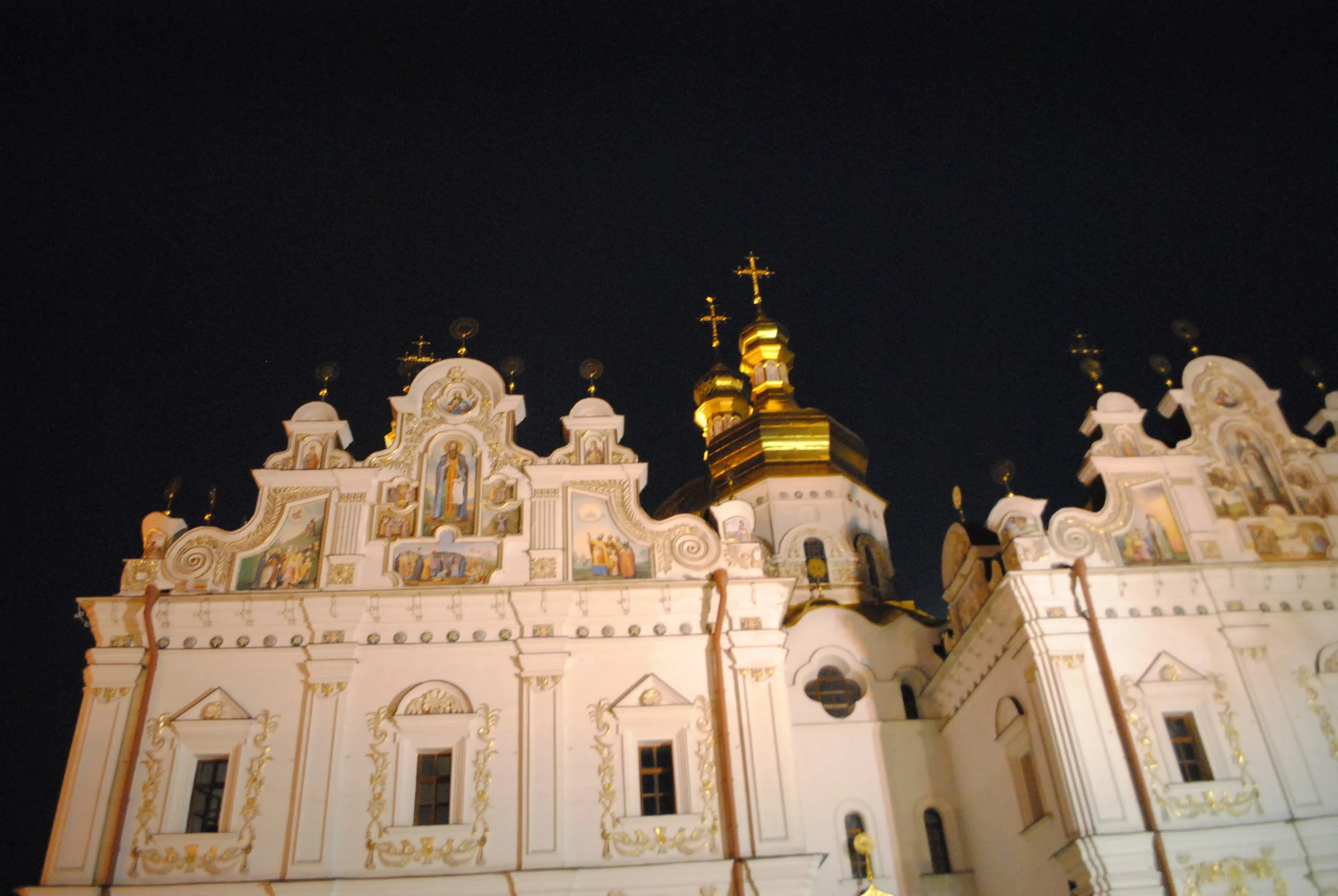 A beautifully illuminated ornate church with white and gold detailing at night.